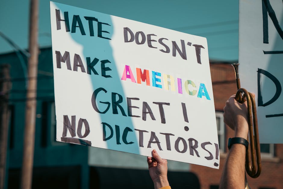 A protest sign with the message 'Hate Doesn't Make America Great!' during a daytime demonstration.