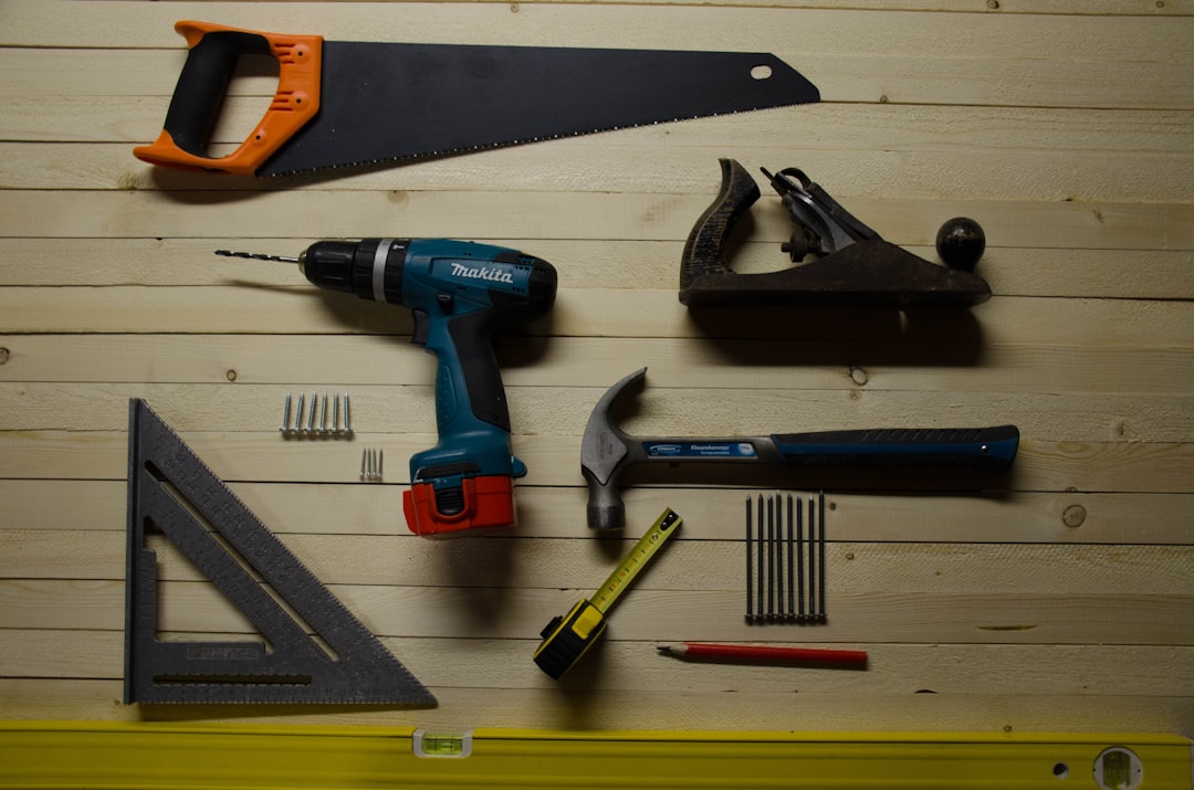 An overhead flat lay of essential woodworking and DIY tools including a saw, drill, hammer, and measuring instruments on...