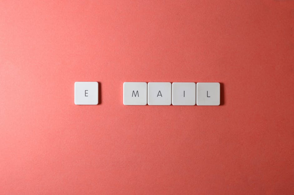 Flat lay of keyboard letter tiles spelling 'email' on coral backdrop